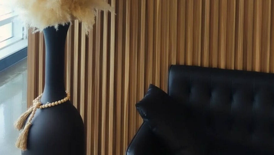 Cozy corner at Incantation Beauty Studio, Calgary, Alberta, CA with a chic black sofa and decorative vase.