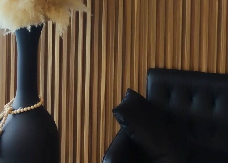 Cozy corner at Incantation Beauty Studio, Calgary, Alberta, CA with a chic black sofa and decorative vase.