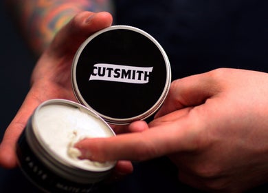 Hands holding Cutsmith styling product container at Cutsmith, Yeadon, England, GB, showcasing grooming essentials.