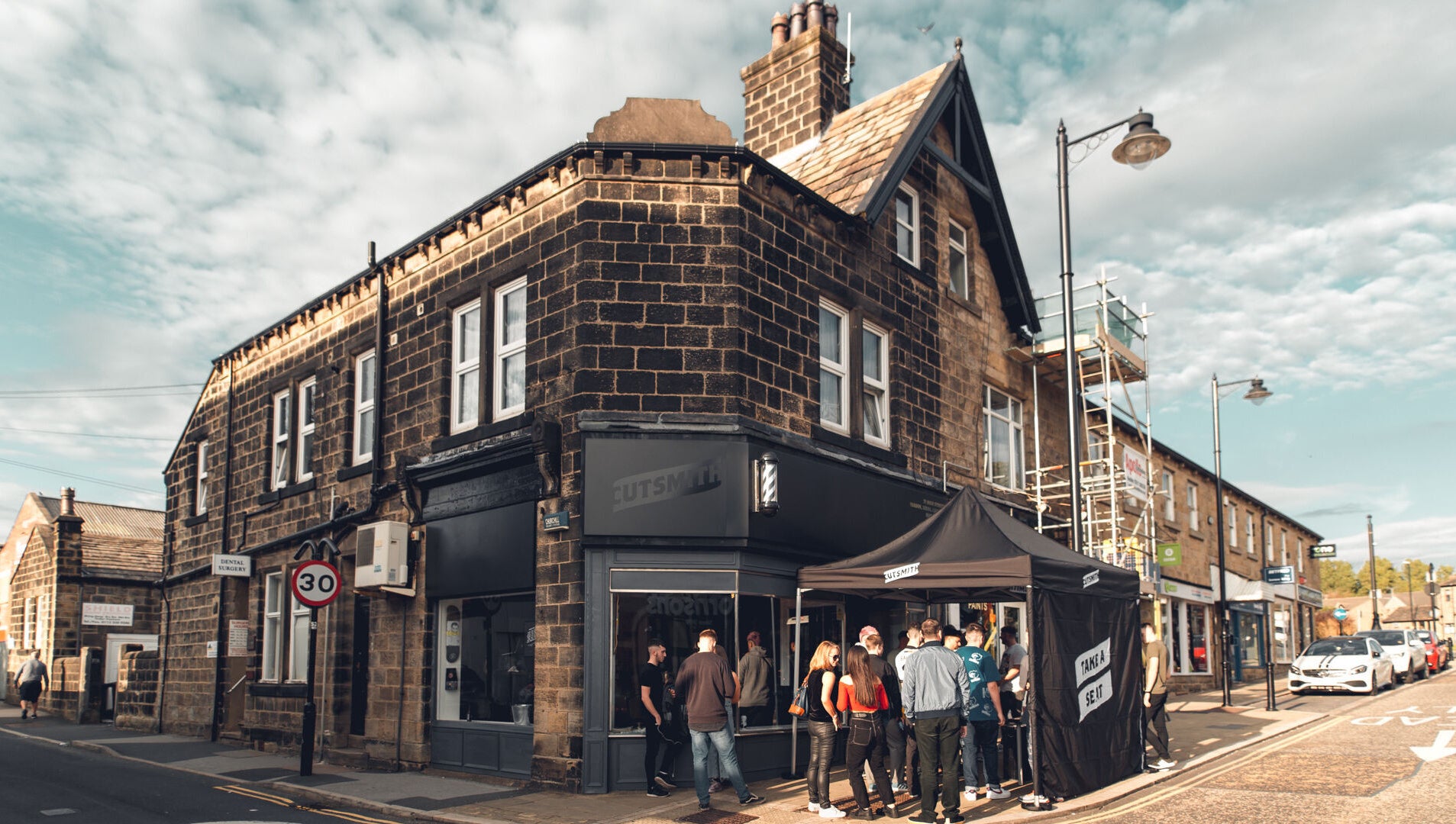Cutsmith salon in Yeadon, England, GB with a crowd outside its charming stone building.