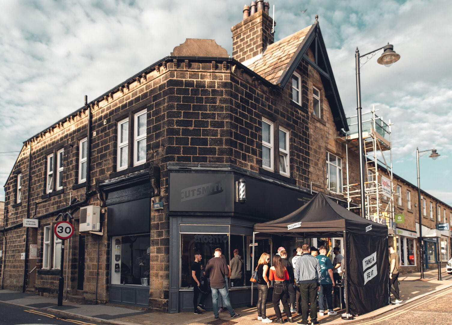 Cutsmith salon in Yeadon, England, GB with a crowd outside its charming stone building.