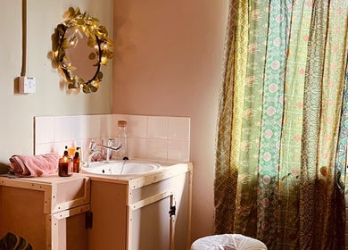 Cozy vanity space at Laura Leongomez, Neyland, Wales, GB with floral mirror and patterned curtains.