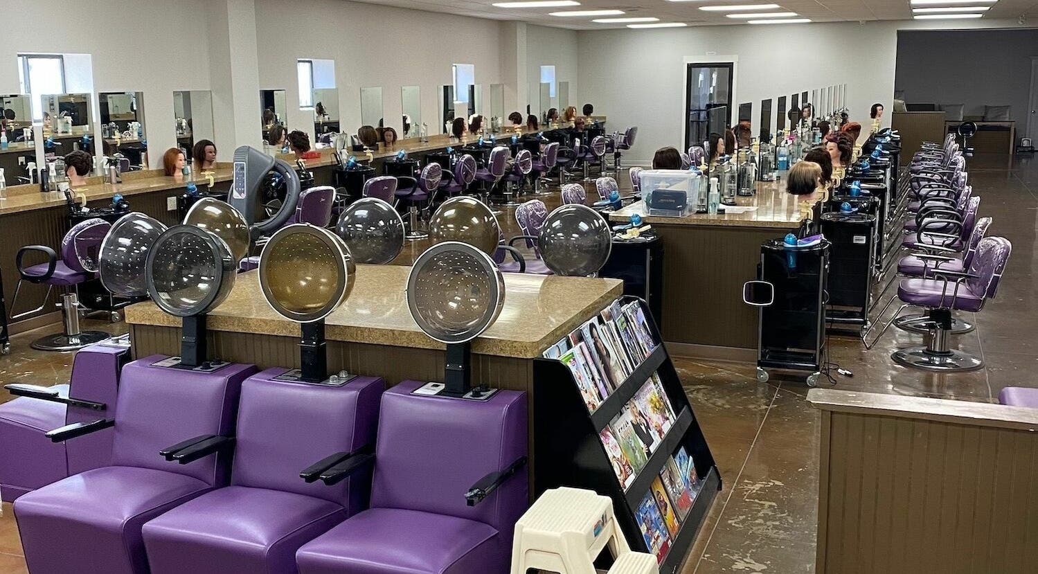 Interior of Hot Springs Beauty College in Hot Springs, Arkansas, US with styling stations and purple chairs.