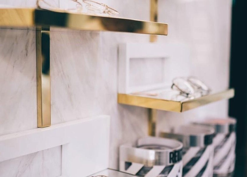 Elegant gold and white shelving at Canton Barber Causeway Bay, Hong Kong Island, HK, displaying grooming items.