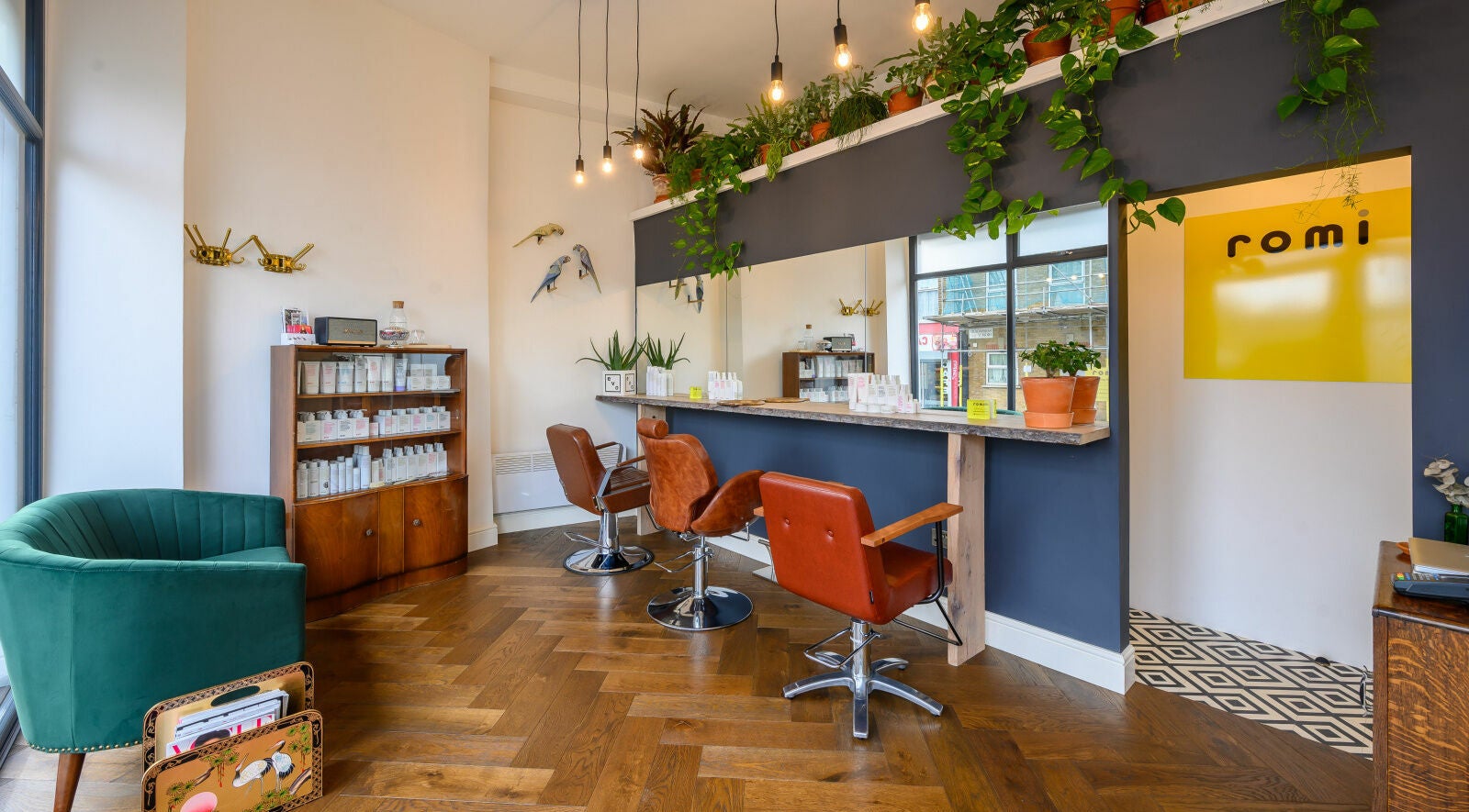 Stylish interior of Romi Salon, London, England, GB, featuring elegant chairs and vibrant decor with plants.