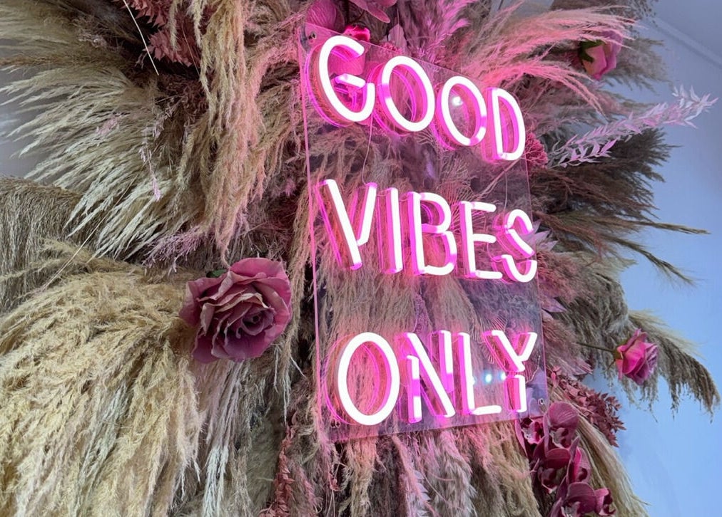 Neon sign 'Good Vibes Only' amid floral decor at Lucy Clydesdale Makeup Brows Lashes, Yarm, England, GB.