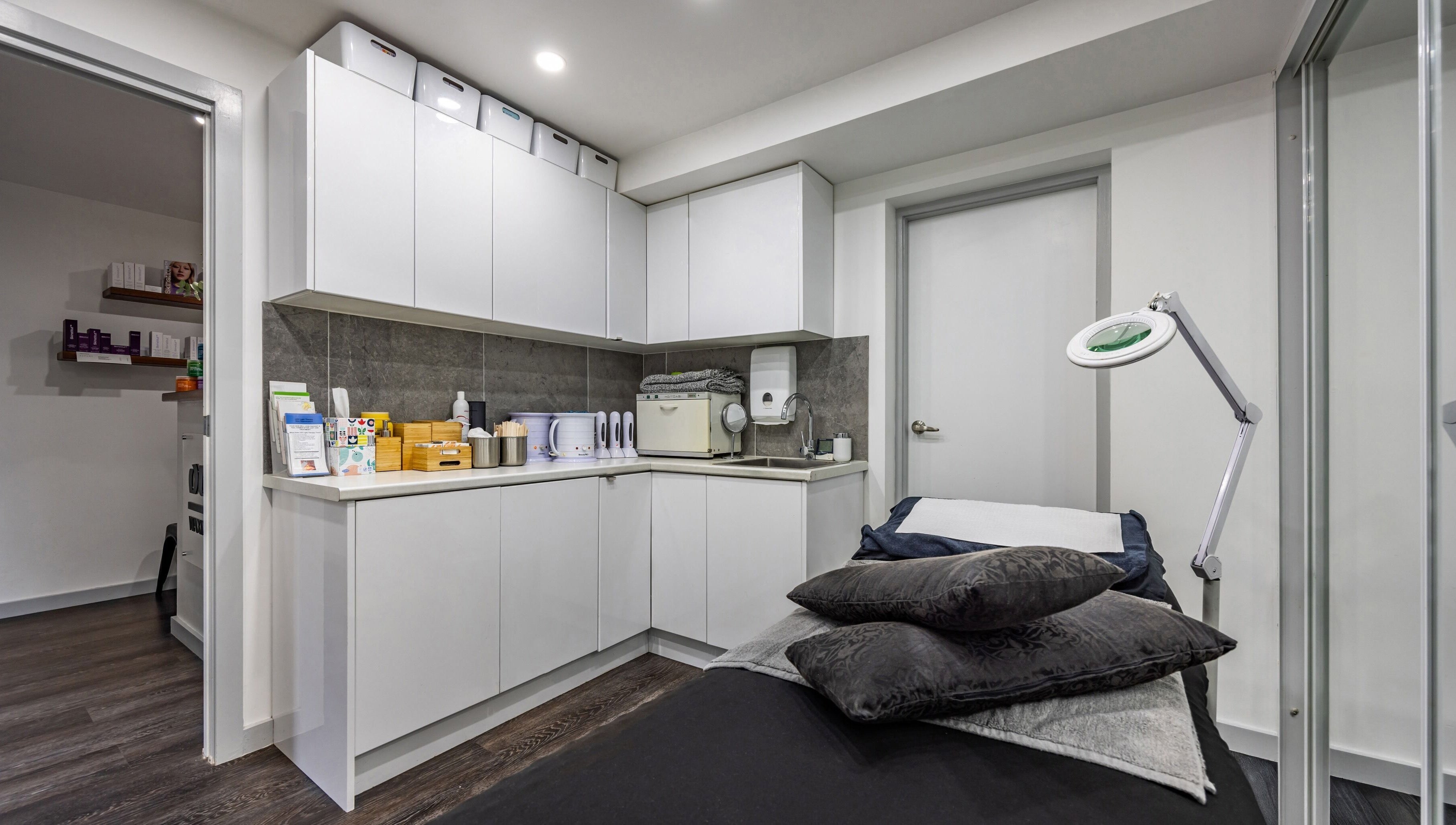 Modern treatment room at Ouch Waxing Studio, Bonnet Bay, New South Wales, AU, featuring sleek cabinetry and a massage bed.
