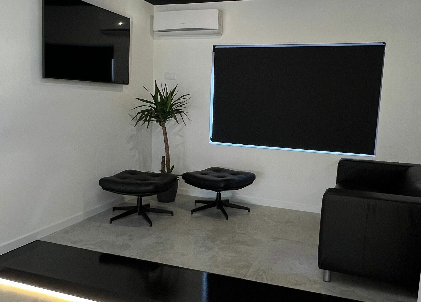 Área de espera elegante e moderna no Blend Men's Salon | Taipas em Guimarães, PT, com cadeira e decoração minimalista.