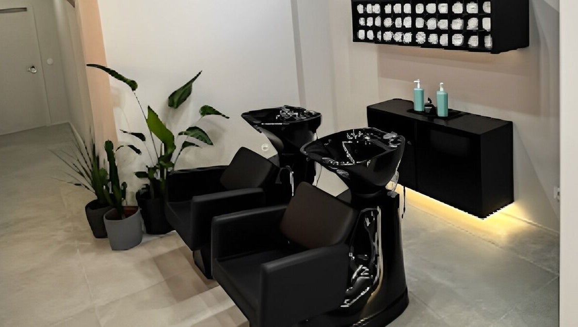 Salão elegante no Blend Men's Salon | Guimarães, com cadeiras pretas e planta decorativa. Localizado em Guimarães, PT.