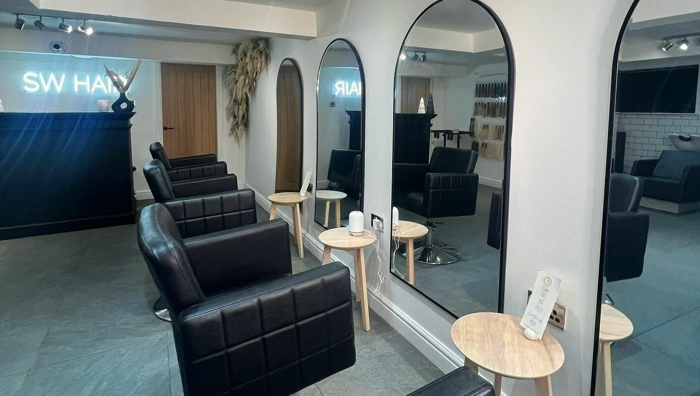 Modern salon interior at SW Hair Extensions, Watnall, England, GB with sleek black chairs and mirrors.