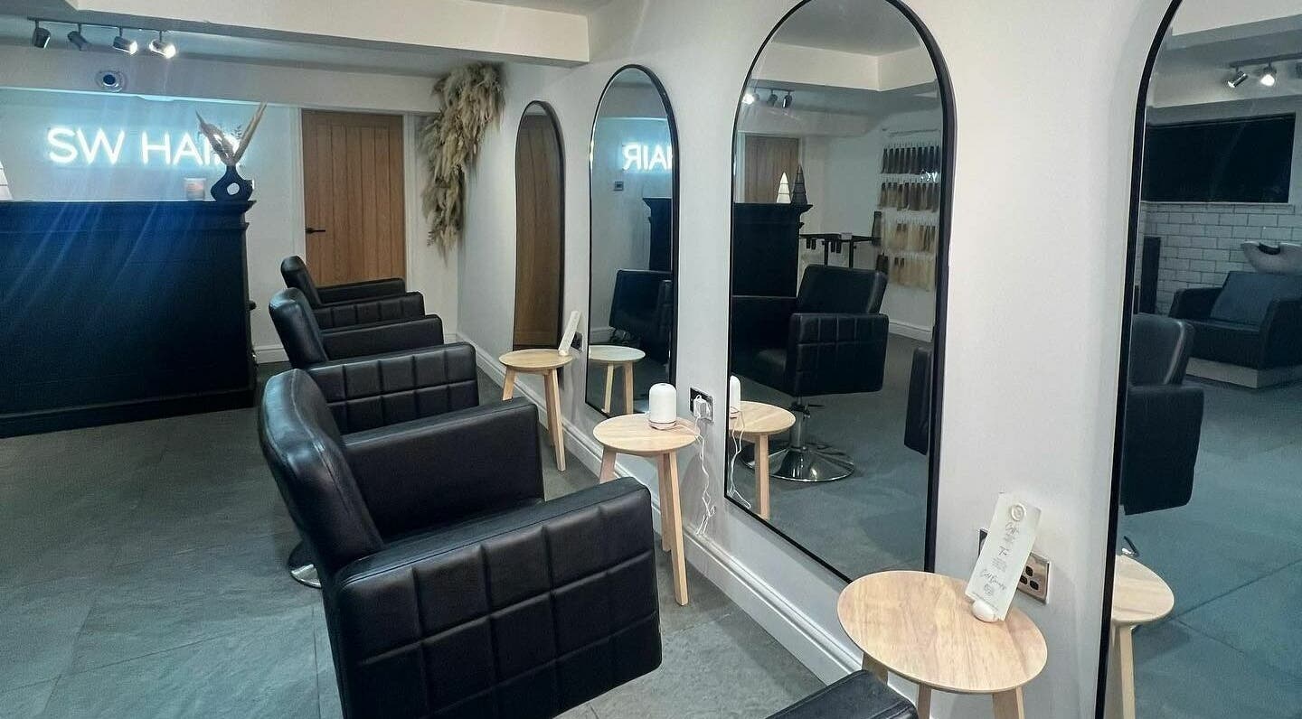 Modern salon interior at SW Hair Extensions, Watnall, England, GB with sleek black chairs and mirrors.