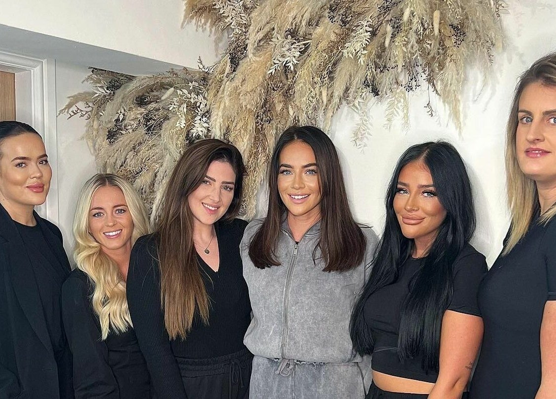 Team at SW Hair Extensions, Watnall, England, GB, posing in front of decorative dried florals indoors.