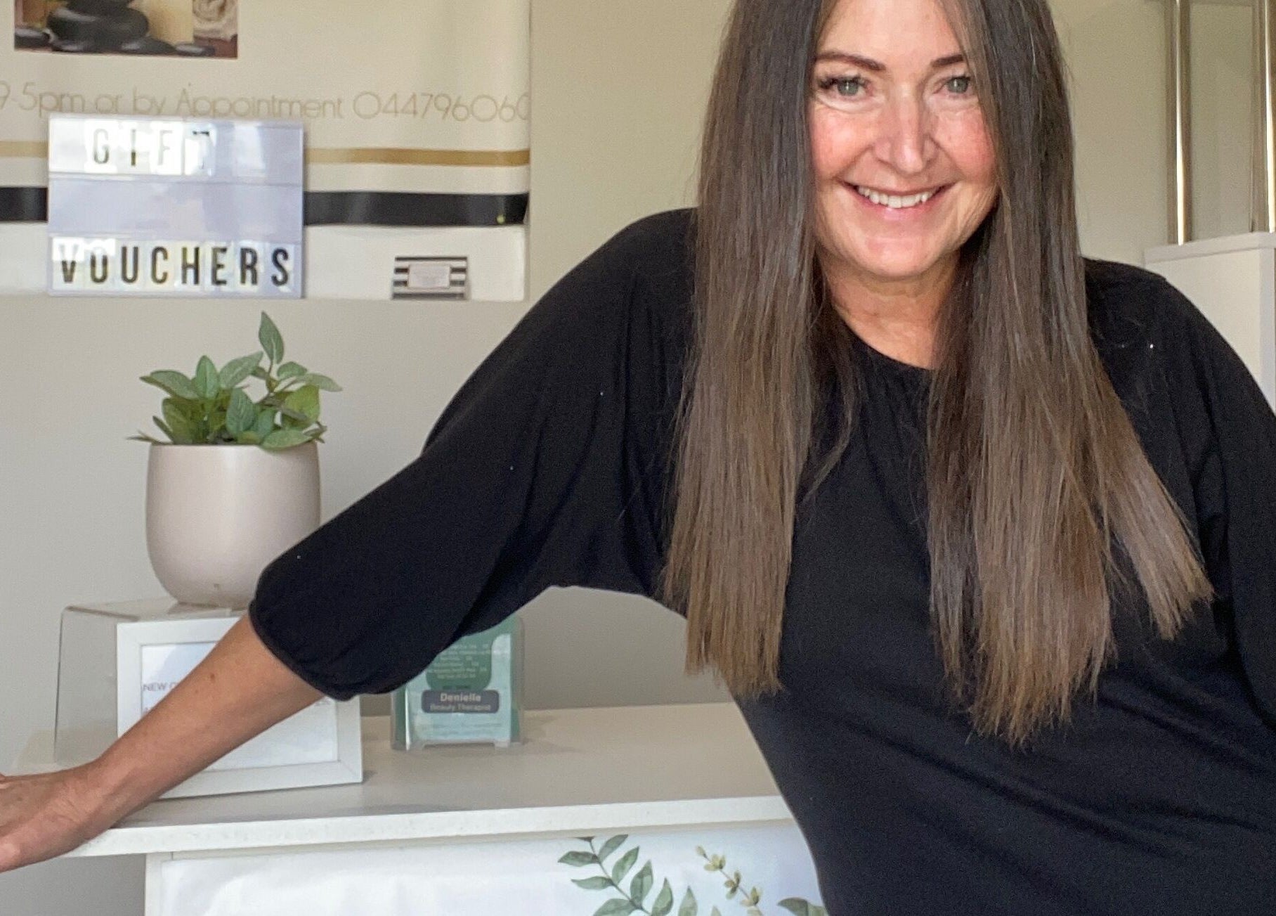 Friendly host at Sunset Waxing Beauty Studio, Melbourne, Victoria, AU, standing by the counter with gift vouchers.