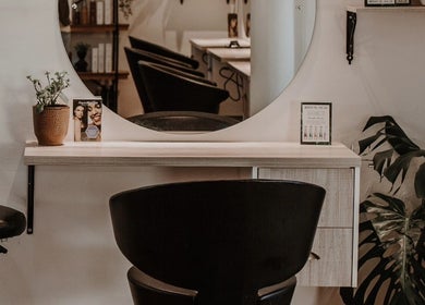 Stylish styling station at Citrine Hair Salon by Layla, Cape Town, Western Cape, ZA featuring a round mirror.