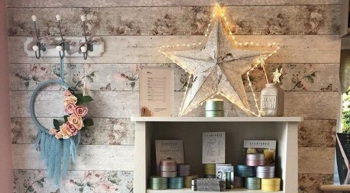 Chic decor at Belle Etoile Beauty in Guernsey, GB: floral wreath and star above display shelves.