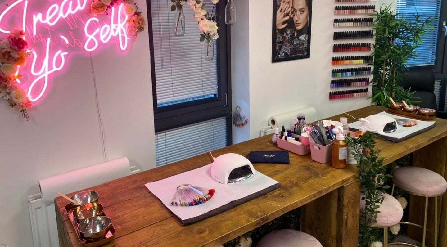 Stylish nail salon setup at The Beauty House, Bristol, England, GB featuring neon sign and colorful polish display.