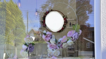 Reflection of floral wreath on window at Holme Beauty & Ear Care, Holme-on-Spalding-Moor, England, GB.