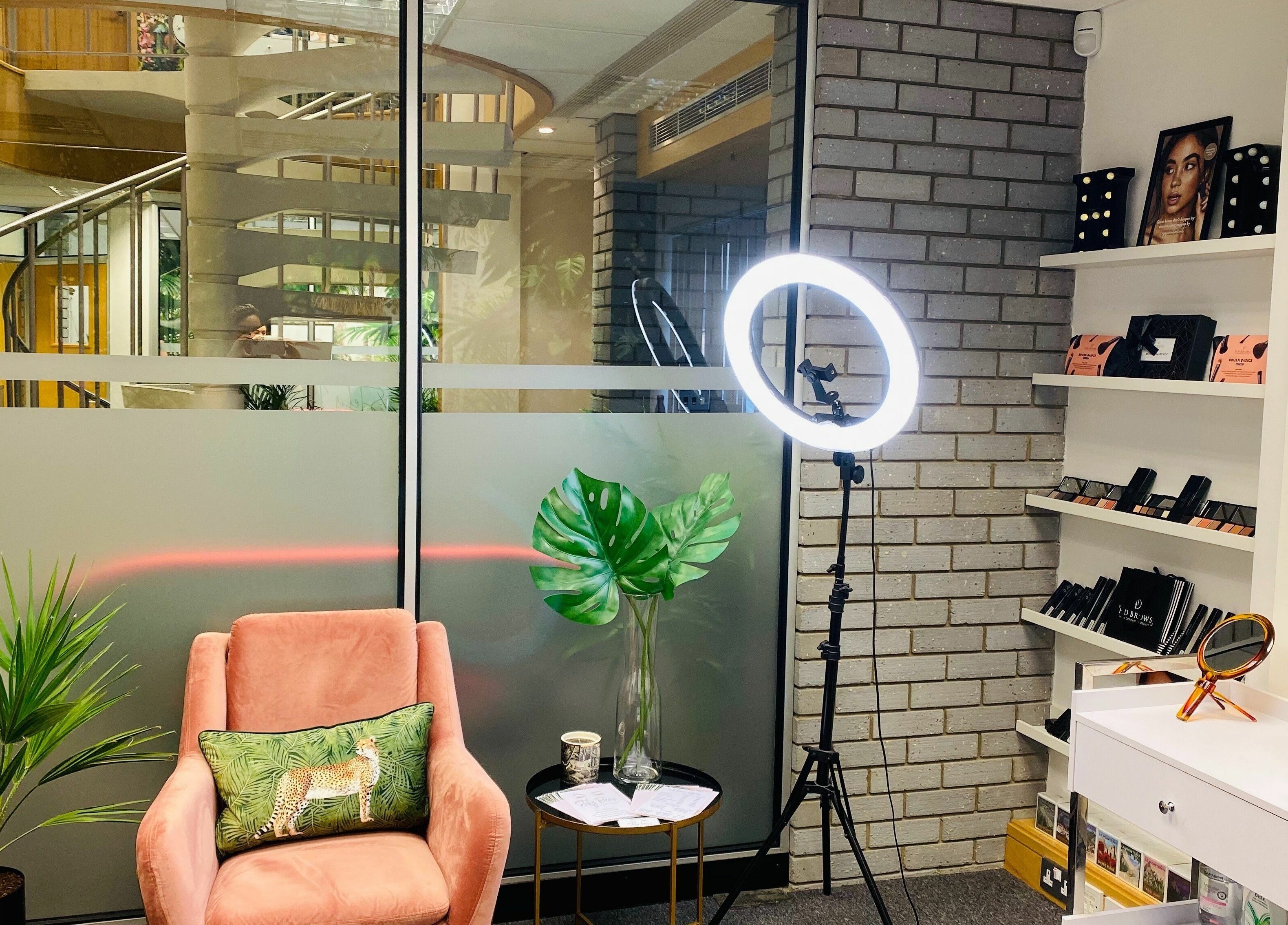Cozy interior of StefyBrows in Harpenden, England, GB with pink chair, ring light, and makeup products.