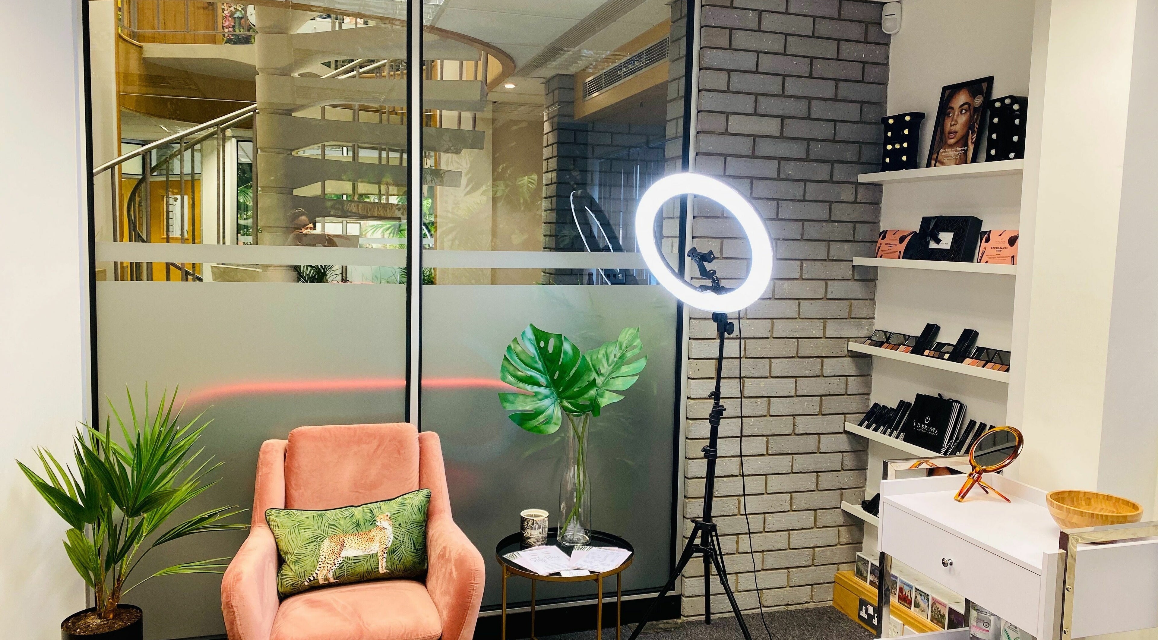 Cozy interior of StefyBrows in Harpenden, England, GB with pink chair, ring light, and makeup products.