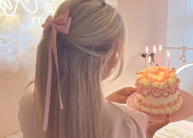 Woman with cake and candles at Jessica Rose Beauty, Leigh on Sea, GB, creating a serene atmosphere.