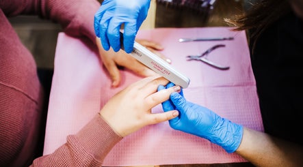Professional manicure at Polished Designs by Danielle, Mount Horeb, Wisconsin, US. Blue-gloved hands filing nails.