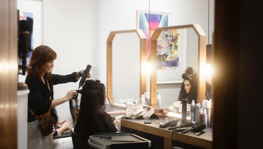 Stylist creating elegant hairstyle at Salome the Salon Stellenbosch, Western Cape, ZA in a modern, light-filled space.