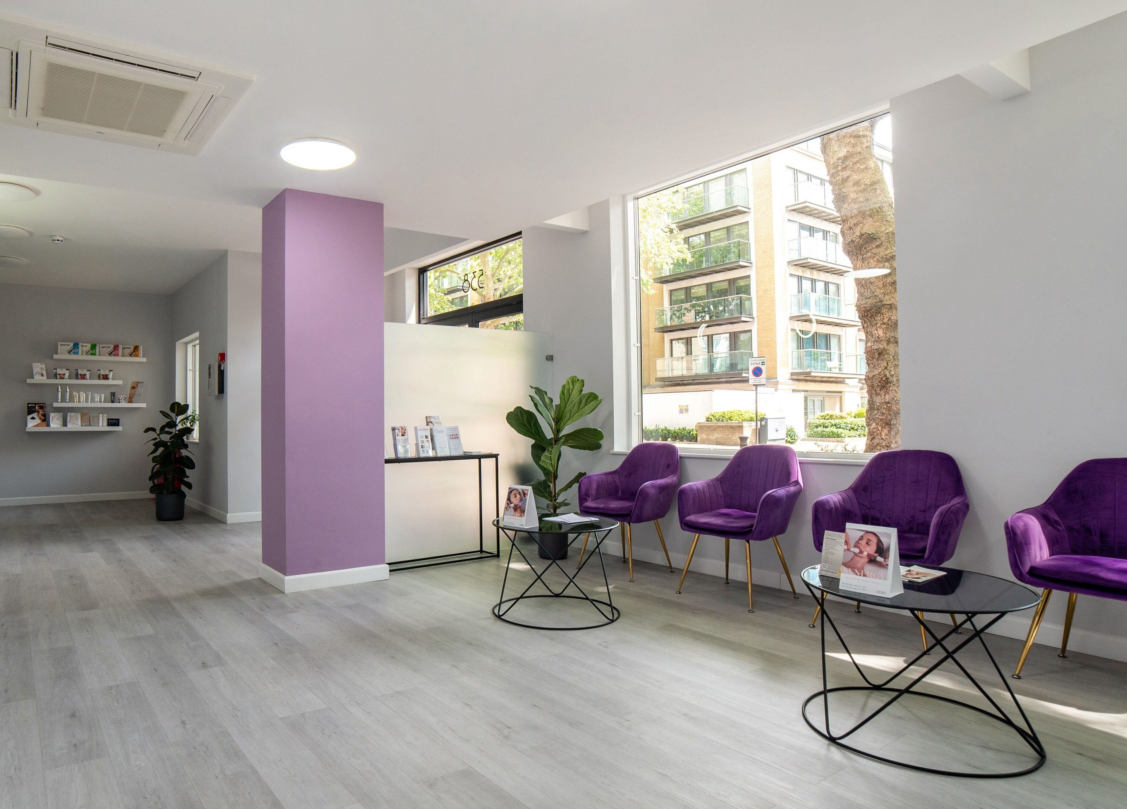 Bright lobby at In-DERM Skin Clinic Chiswick, London, England, GB, featuring purple chairs and modern decor.