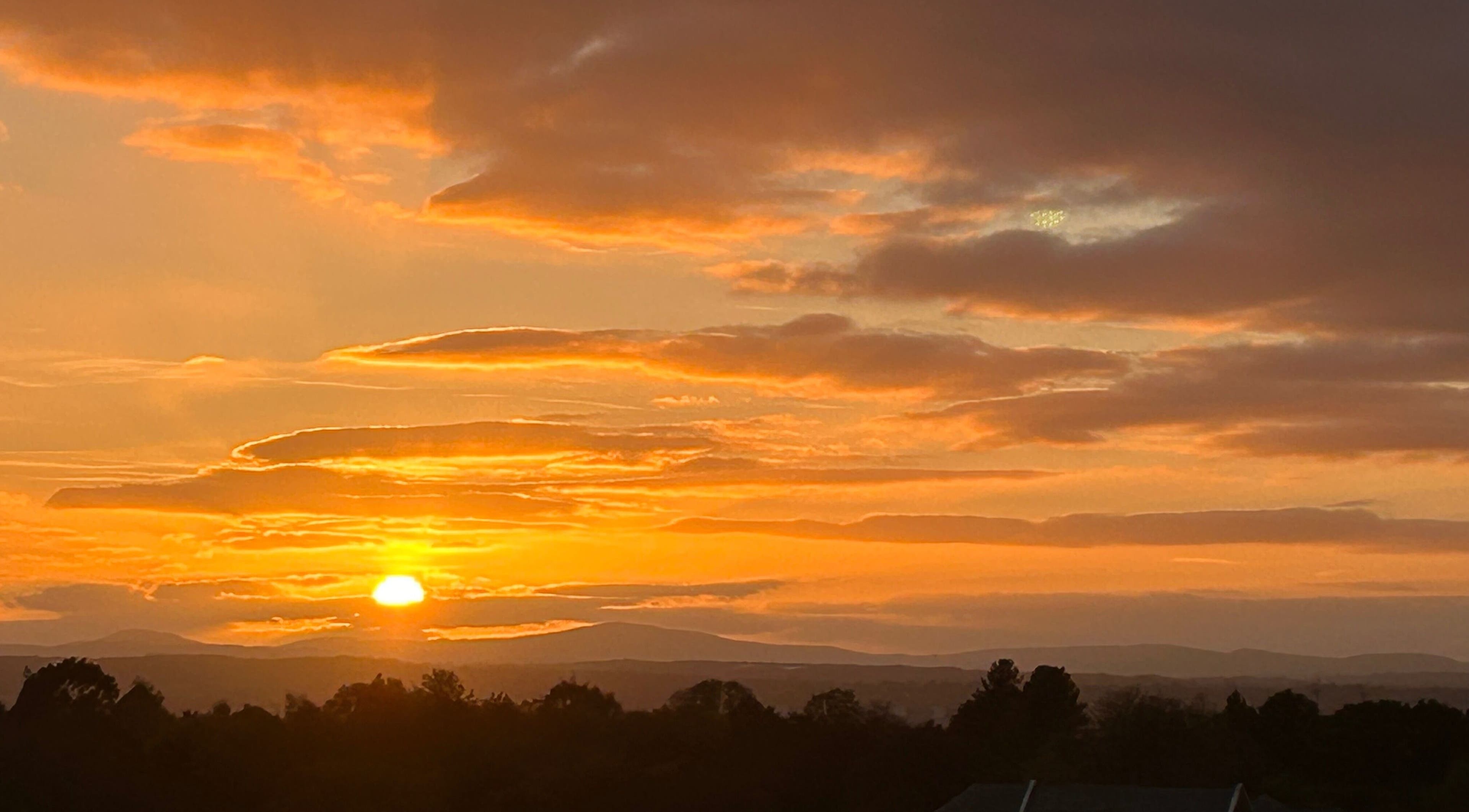 Breathtaking sunset over Rochford seen from Lymphatics Ltd, capturing vibrant hues and serene silhouettes.