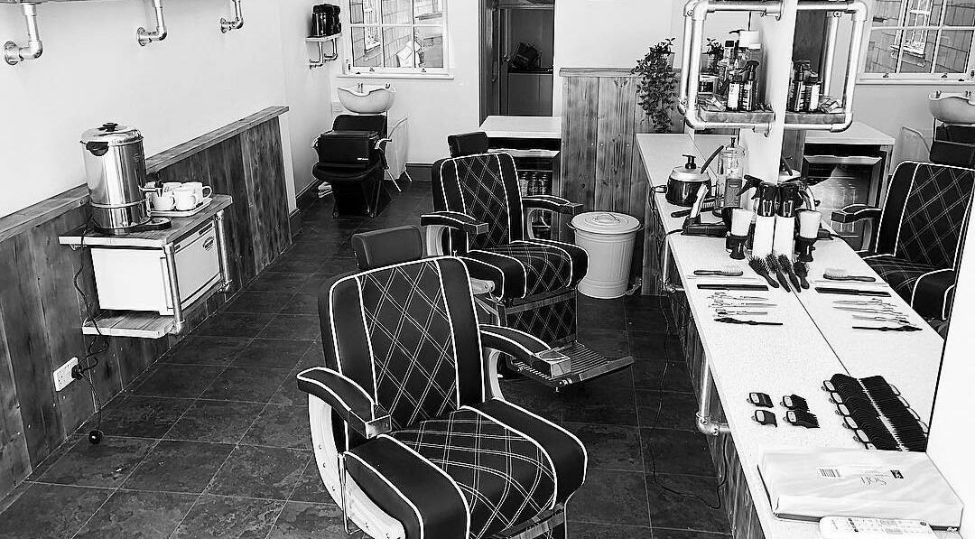 Interior of Fore St Barbers in Totnes, England, GB featuring vintage chairs and grooming tools.