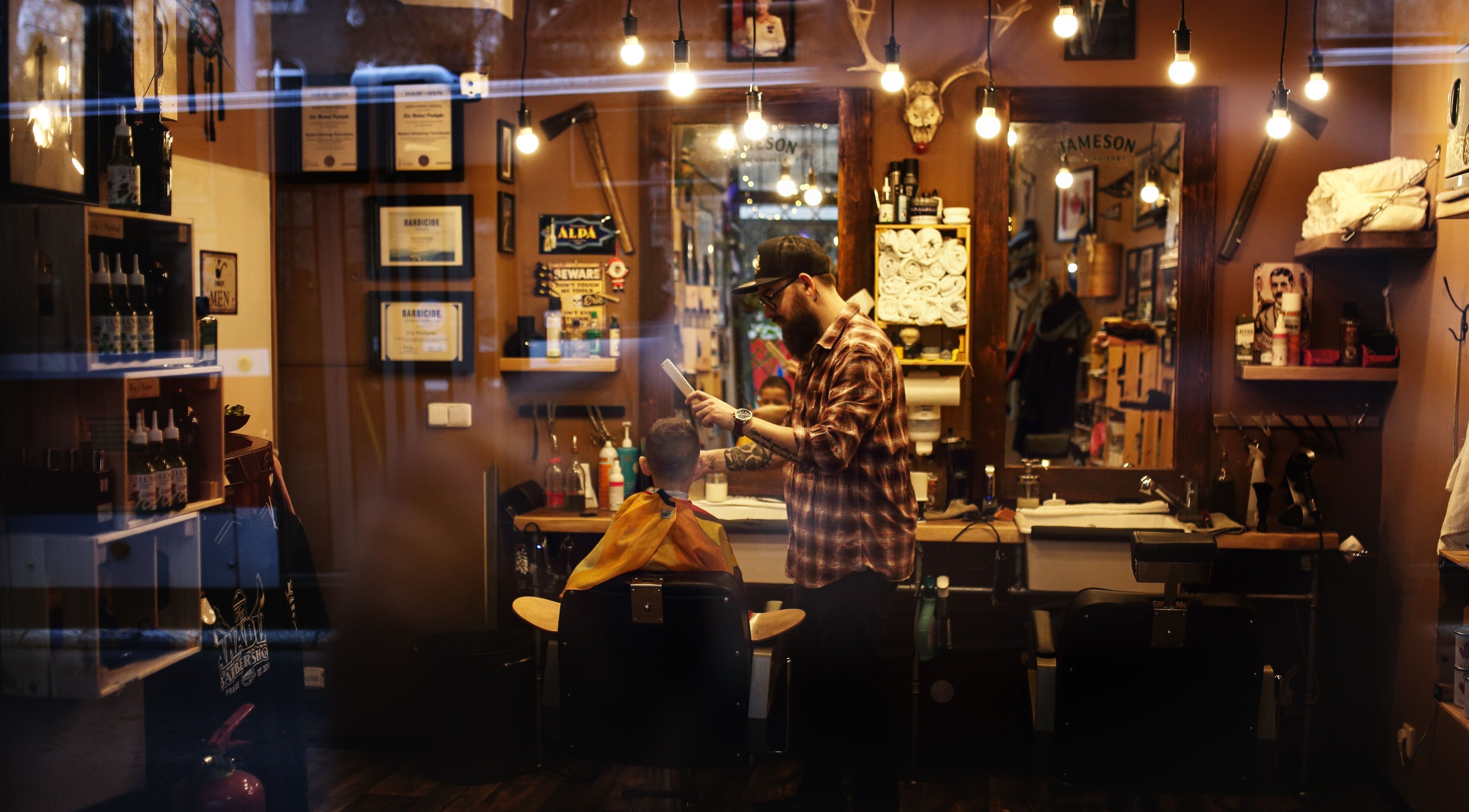 Interior of The Canadian Barbershop in Praha, CZ, showcasing a barber styling a customer's hair.