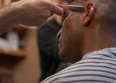 Expert shave at The Canadian Barbershop, Praha, Hlavní město Praha, CZ. Close-up of client receiving precise hairline trim.