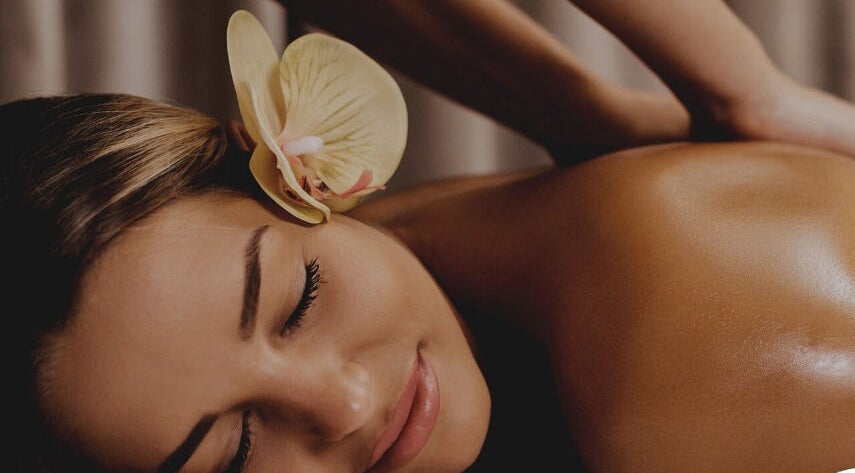Relaxing massage at Hawaiian Hush Home Service - Dubai Only in Dubai, Dubai, AE with an orchid on woman's hair.