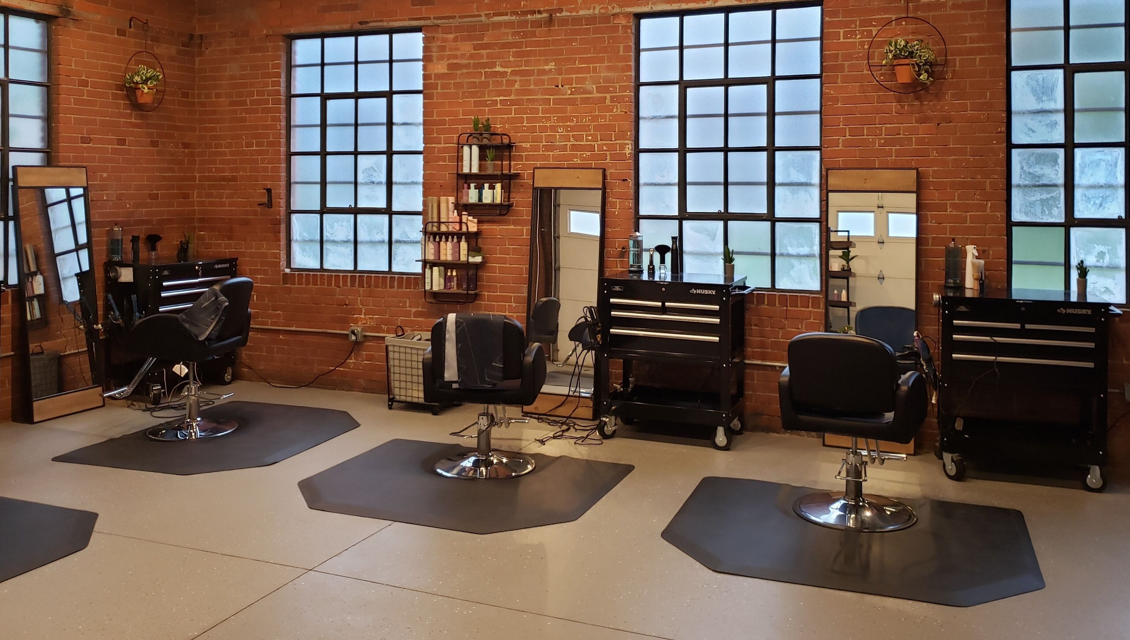 Chic, modern interior of Deeprock Salon in Oklahoma City, Oklahoma, US with styling stations and brick walls.