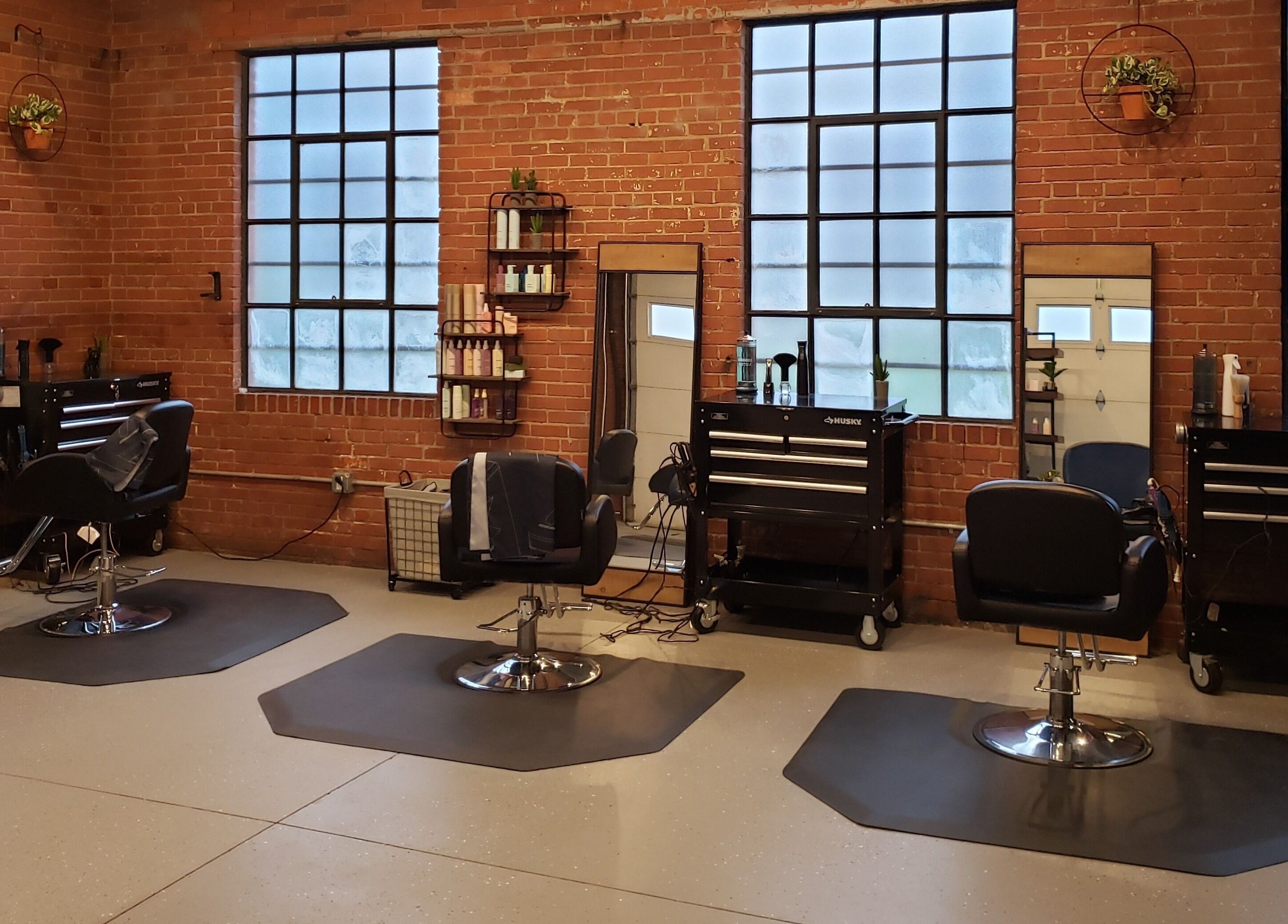 Chic, modern interior of Deeprock Salon in Oklahoma City, Oklahoma, US with styling stations and brick walls.