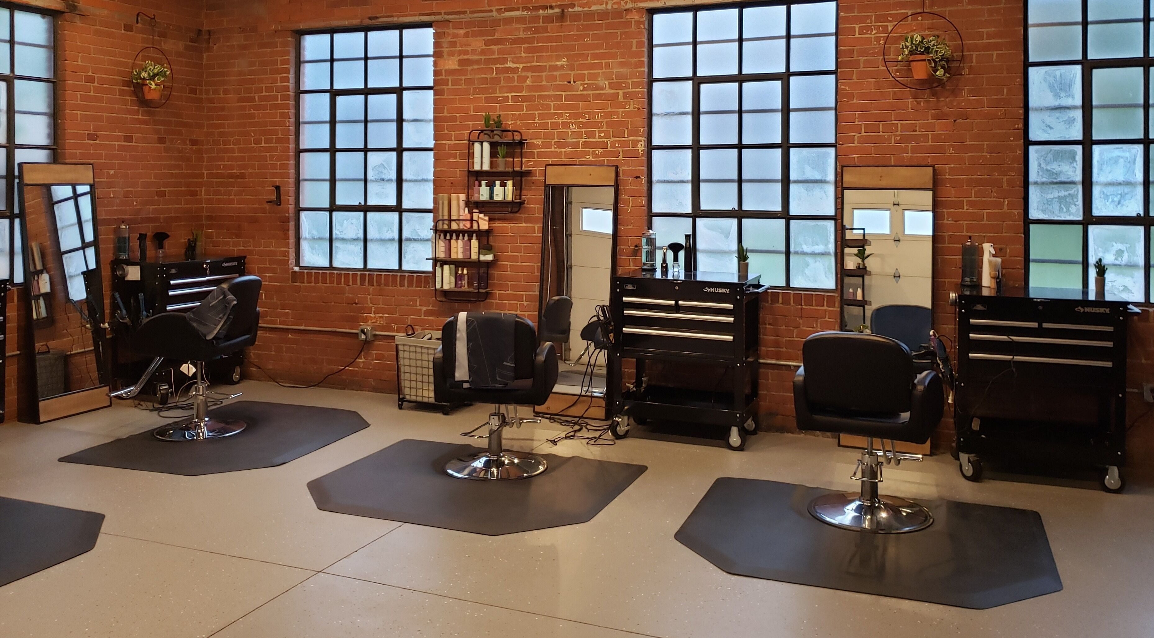 Chic, modern interior of Deeprock Salon in Oklahoma City, Oklahoma, US with styling stations and brick walls.
