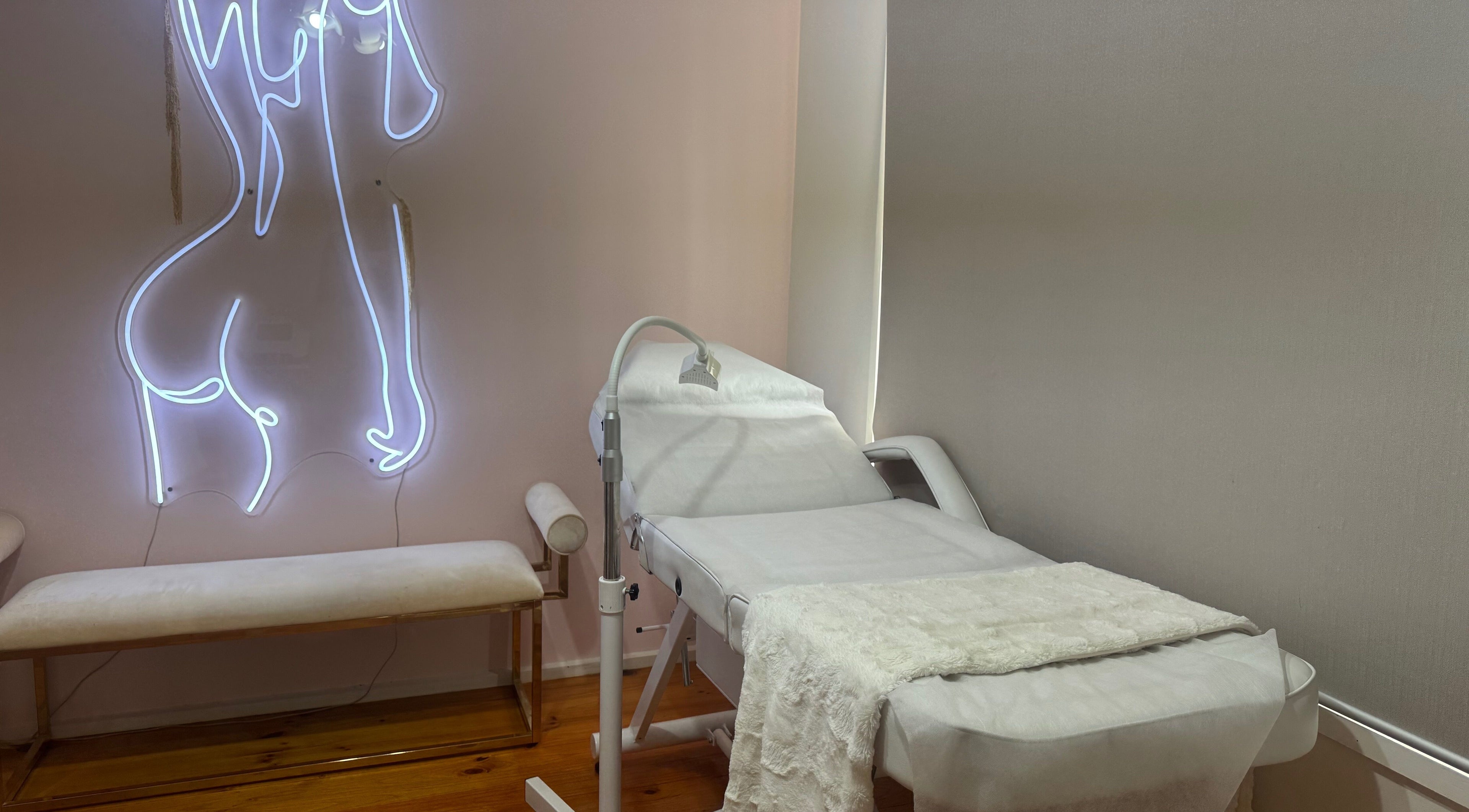 Calm therapy room at Luxe Contouring By Sofia, Melbourne, Victoria, AU with treatment bed and artistic neon decor.