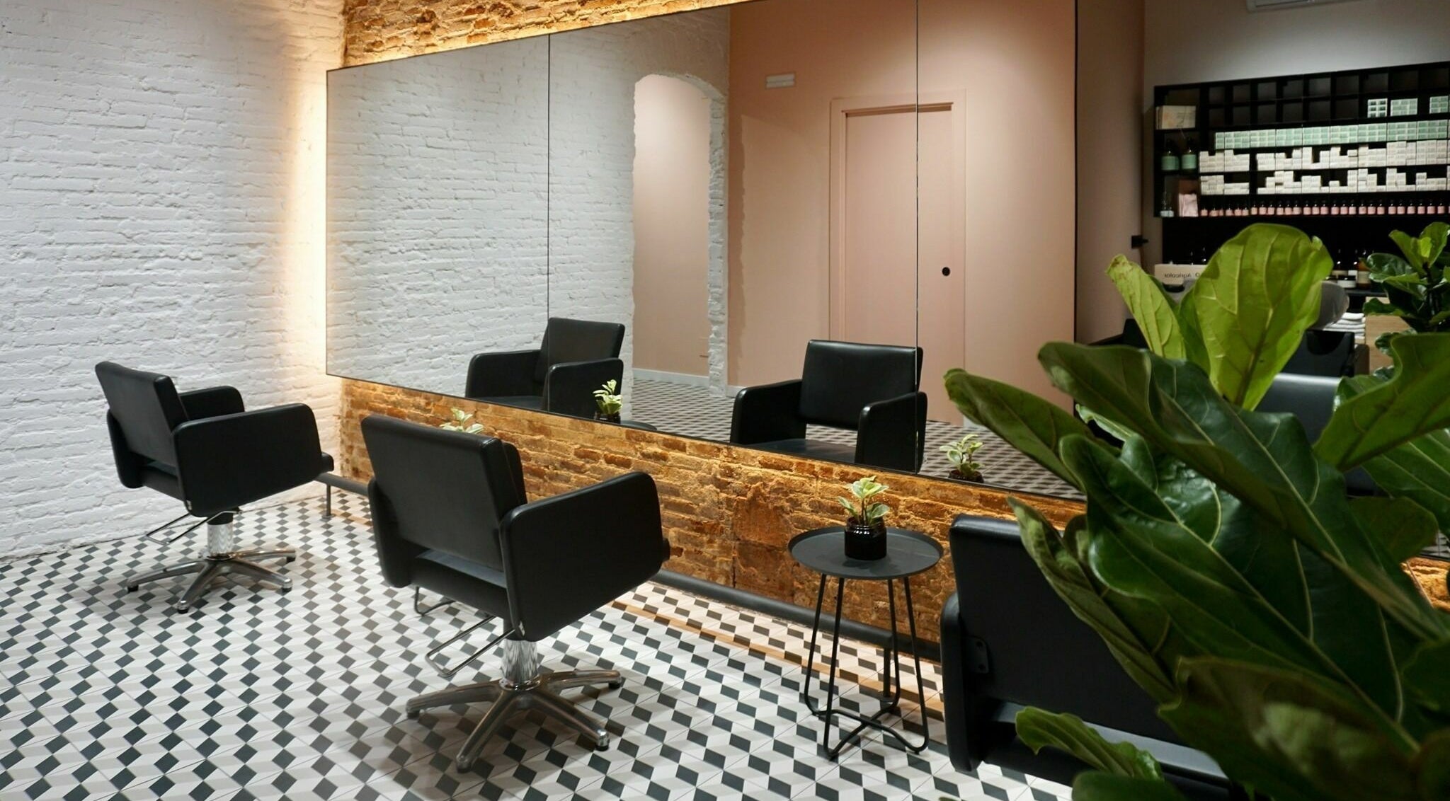 Interior elegante de Lab4Hair en Barcelona, Catalunya, ES, con sillas negras y espejo grande en muro de ladrillo.