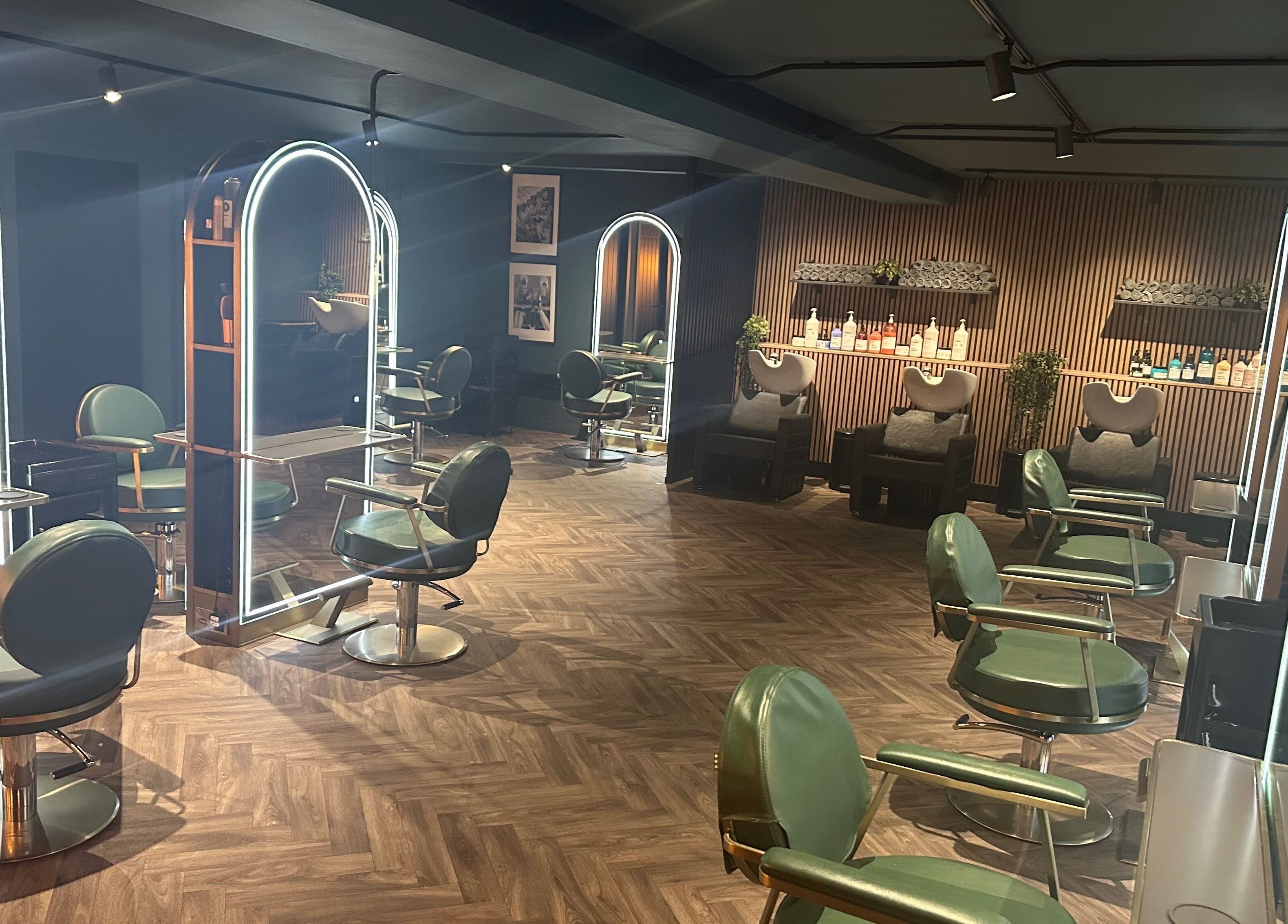 Chic interior of Chandler and Co. in Bedale, England, GB featuring modern salon chairs and illuminated mirrors.