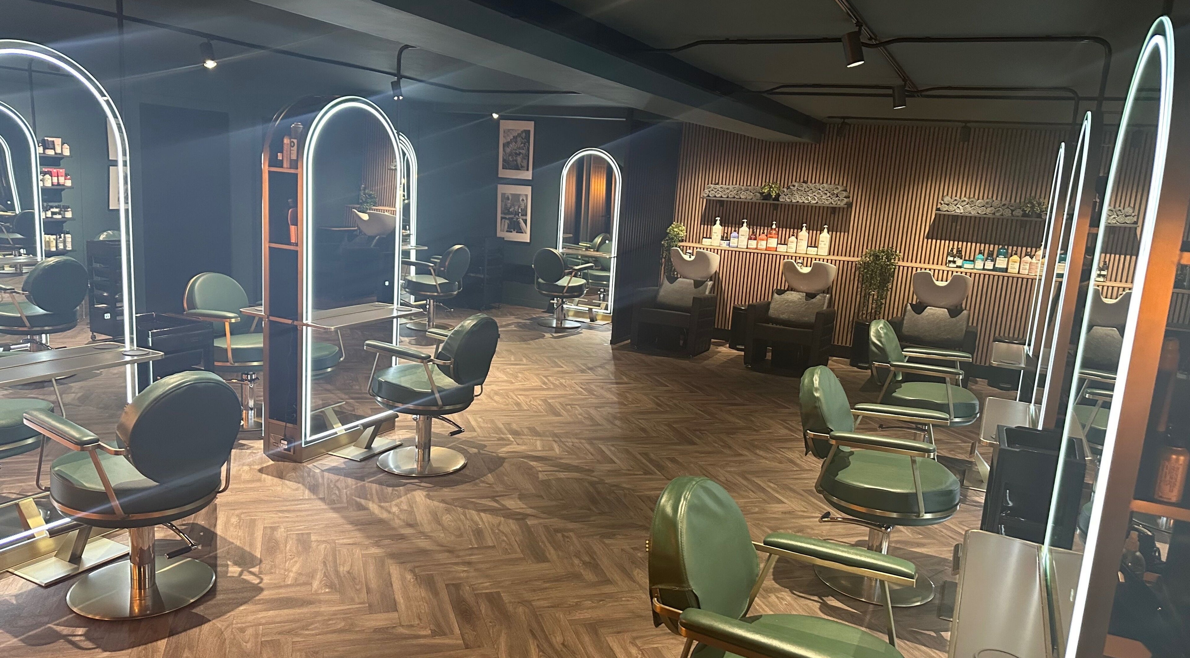 Chic interior of Chandler and Co. in Bedale, England, GB featuring modern salon chairs and illuminated mirrors.