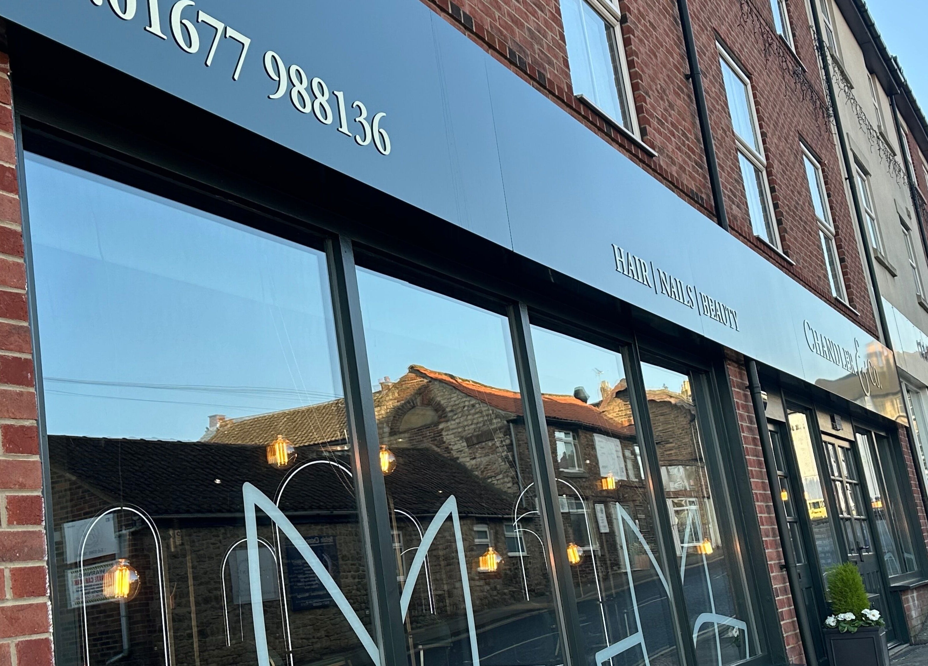 Chandler and Co. storefront in Bedale, England, GB with elegant signage and reflective glass windows.