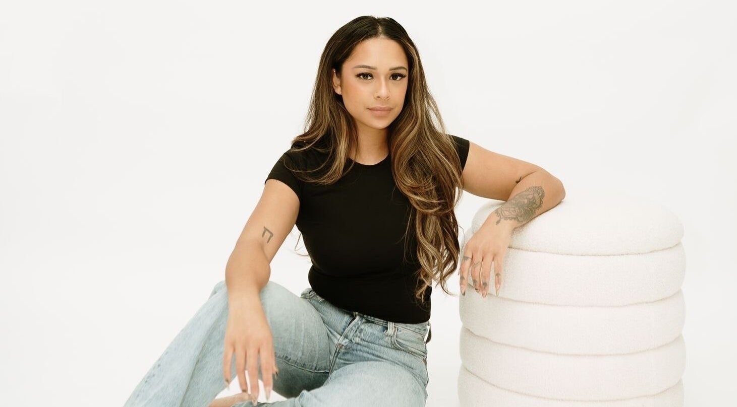 A person sitting gracefully beside a white ottoman at Glamour Queen Artistry Inc., Coquitlam, British Columbia, CA.