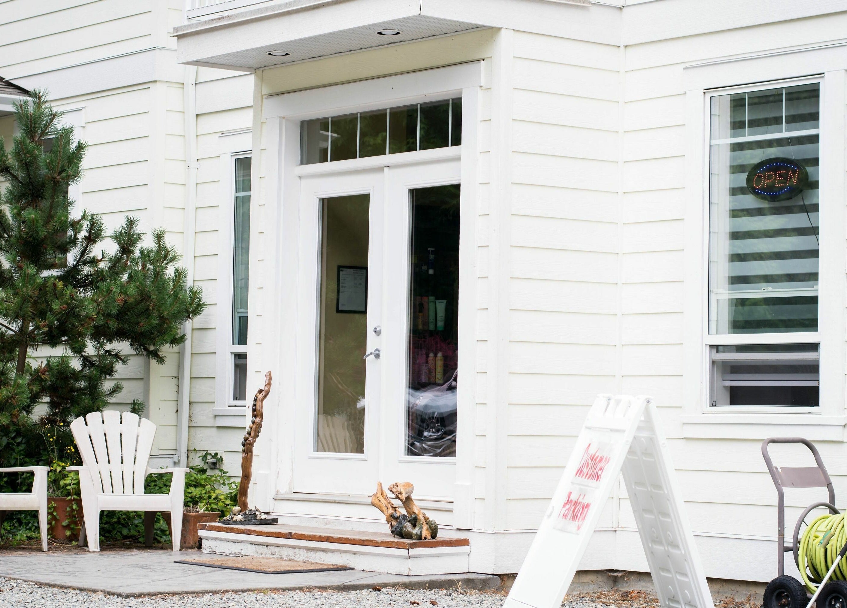 Entrance of Kat's Hair Studio in Sooke, British Columbia, CA with inviting white chairs and greenery.