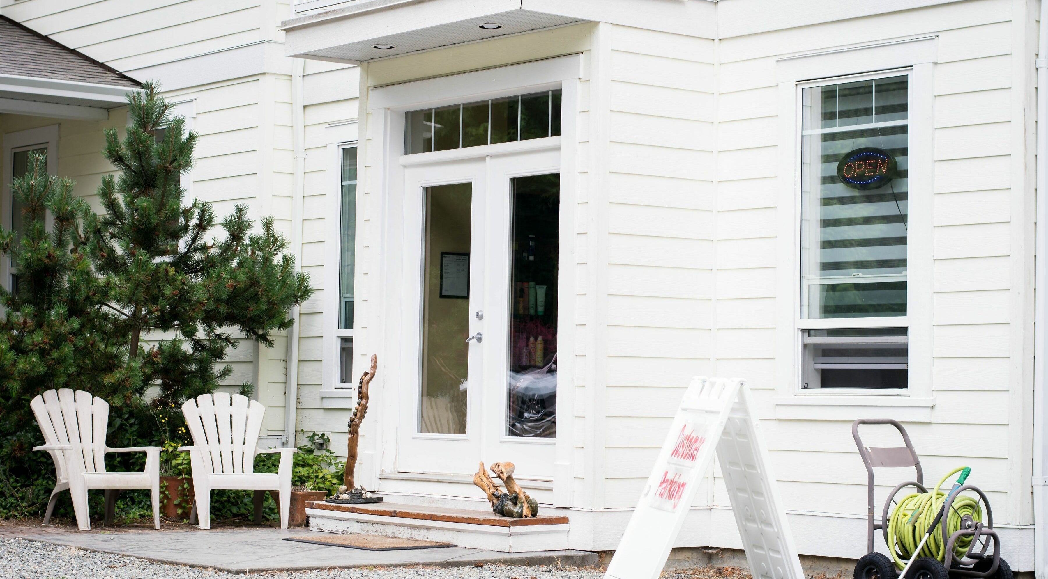 Entrance of Kat's Hair Studio in Sooke, British Columbia, CA with inviting white chairs and greenery.