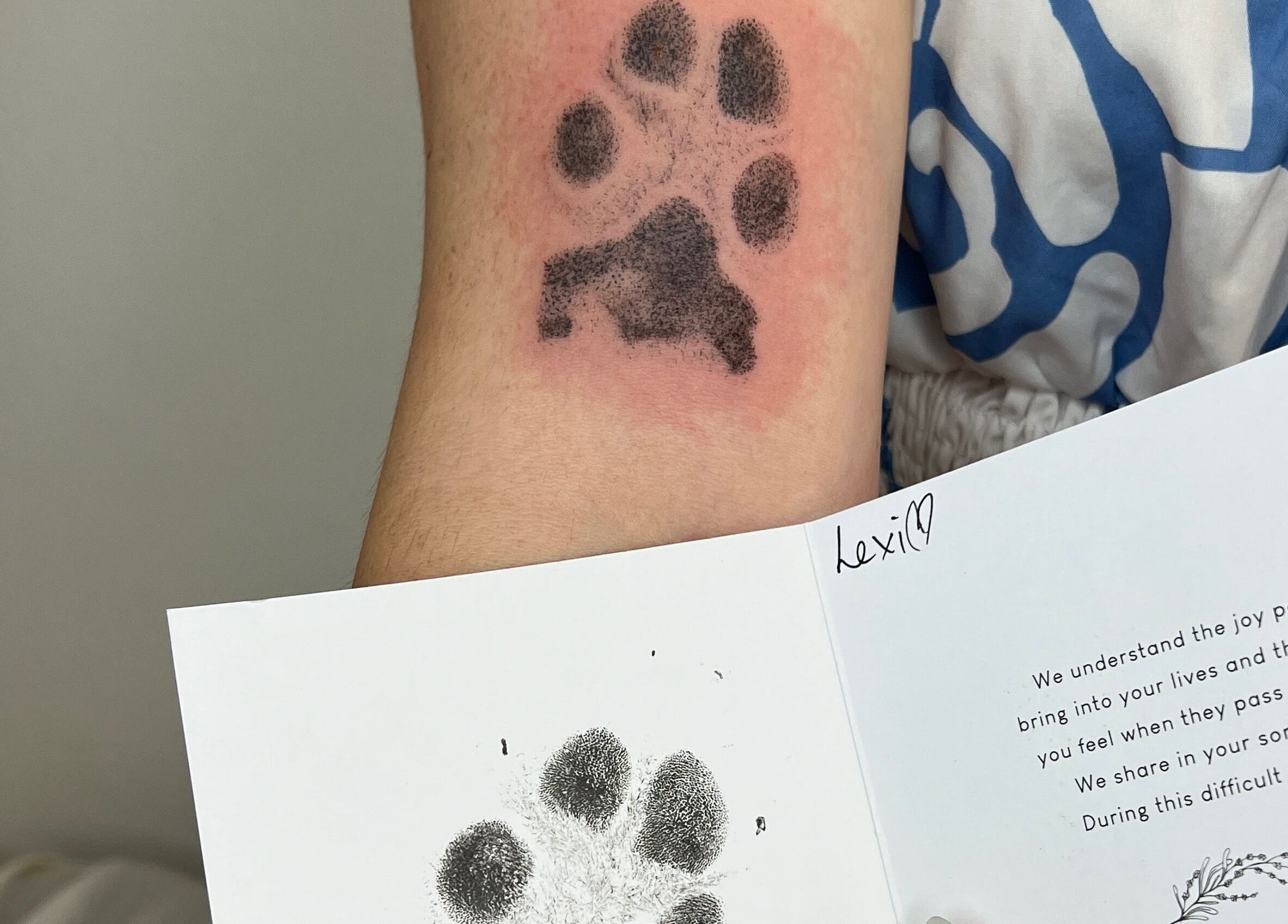 Tattoo of a paw print on arm at Inkd Aesthetics, Surfers Paradise, Queensland, AU, next to memorial card.