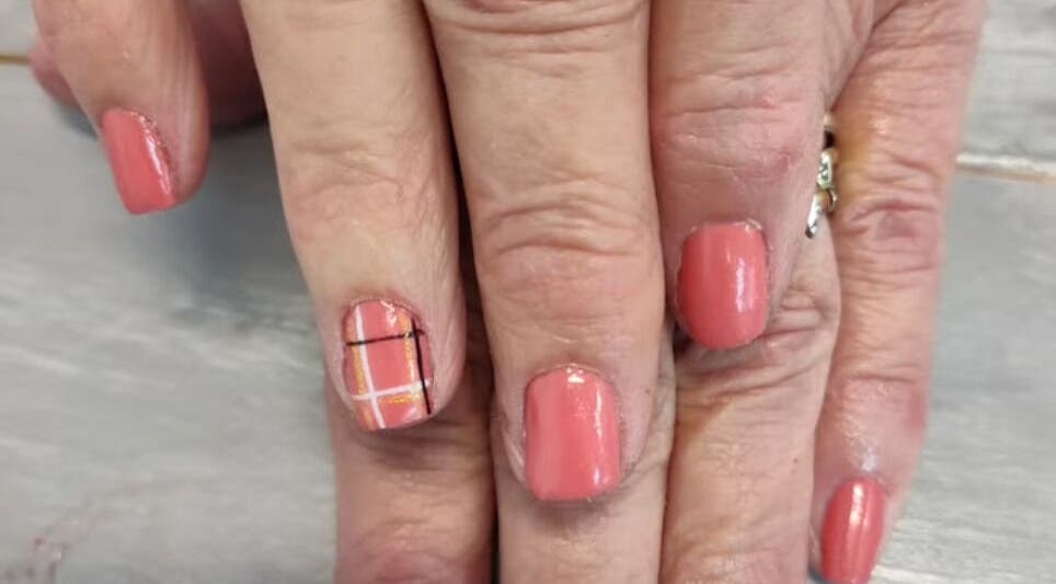 Elegant coral manicure with plaid accent nail at Pedi Lounge Nail Salon, Anderson, Indiana, US.