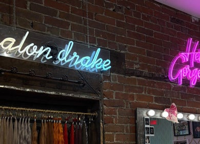 Enseignes au néon à Salon Drake, Montréal, Québec, CA, sur un mur de briques avec extensions de cheveux.