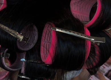 Gros plans de rouleaux rose sur cheveux noirs chez Salon Drake, Montréal, Québec, CA.