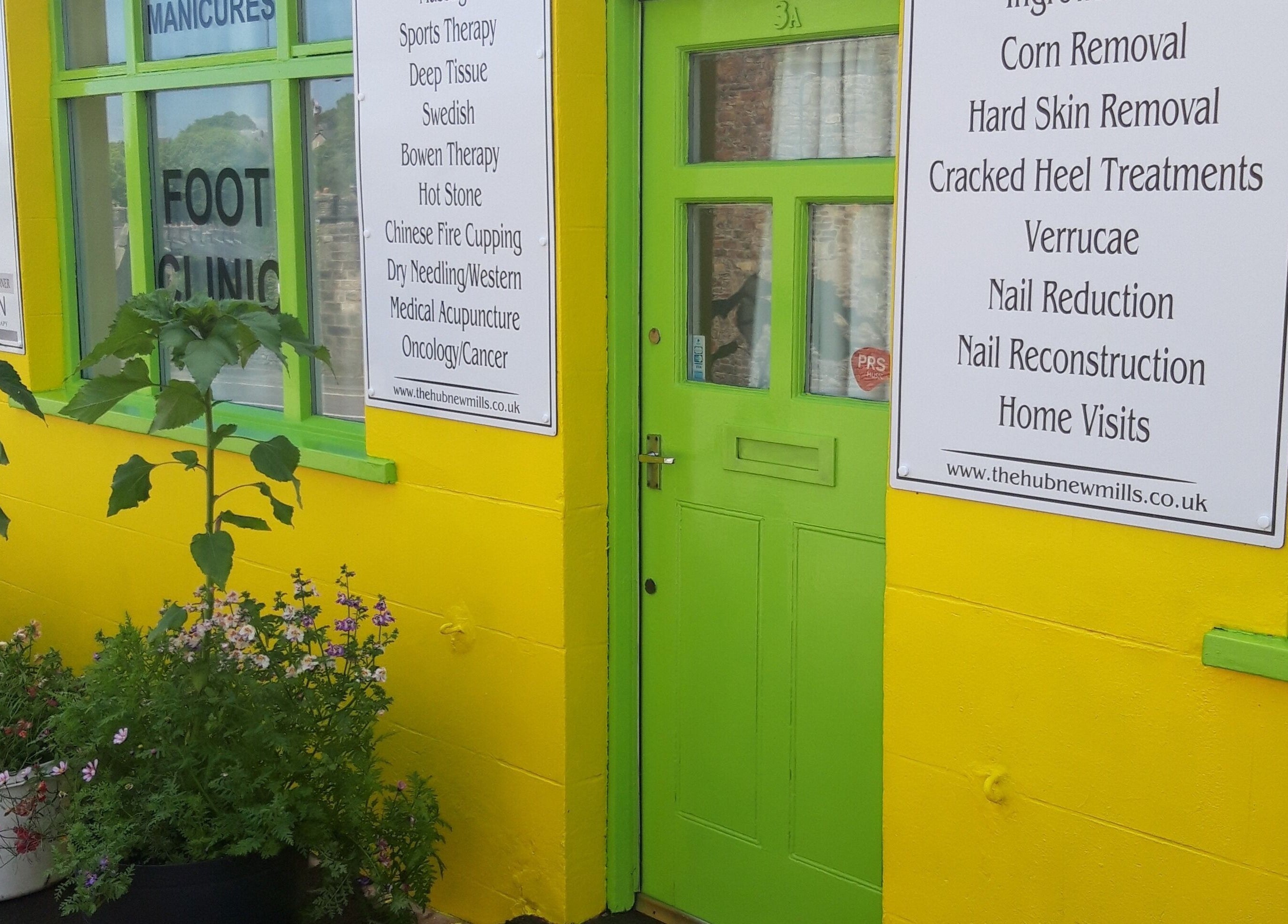 Bright yellow and green entry of The Hub New Mills, New Mills, England. Sign details wellness services offered.