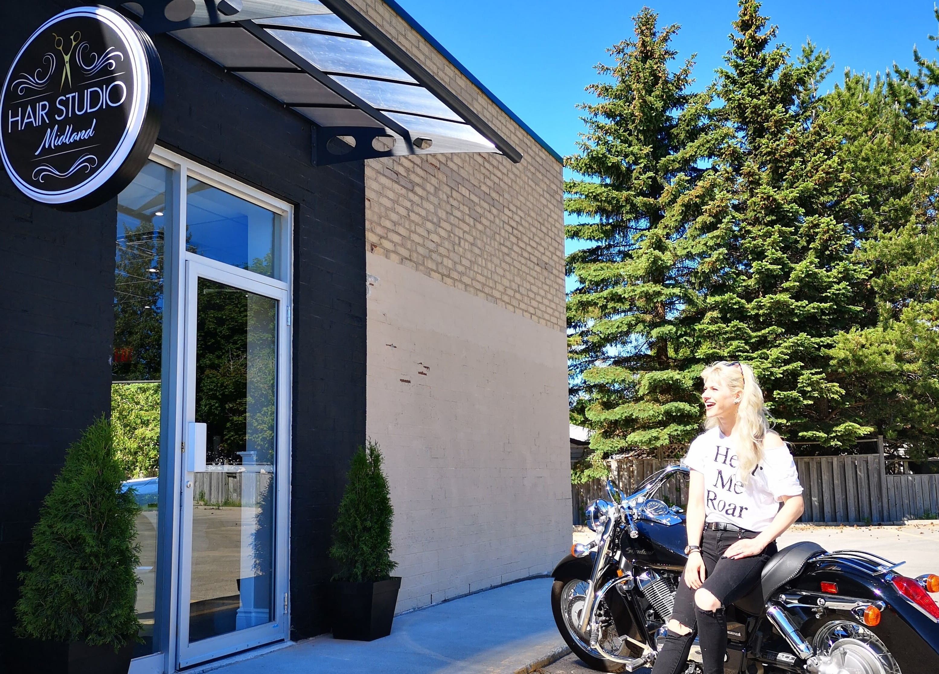 Front of Hair Studio Midland, Midland, Ontario, CA with a woman sitting on a motorcycle.