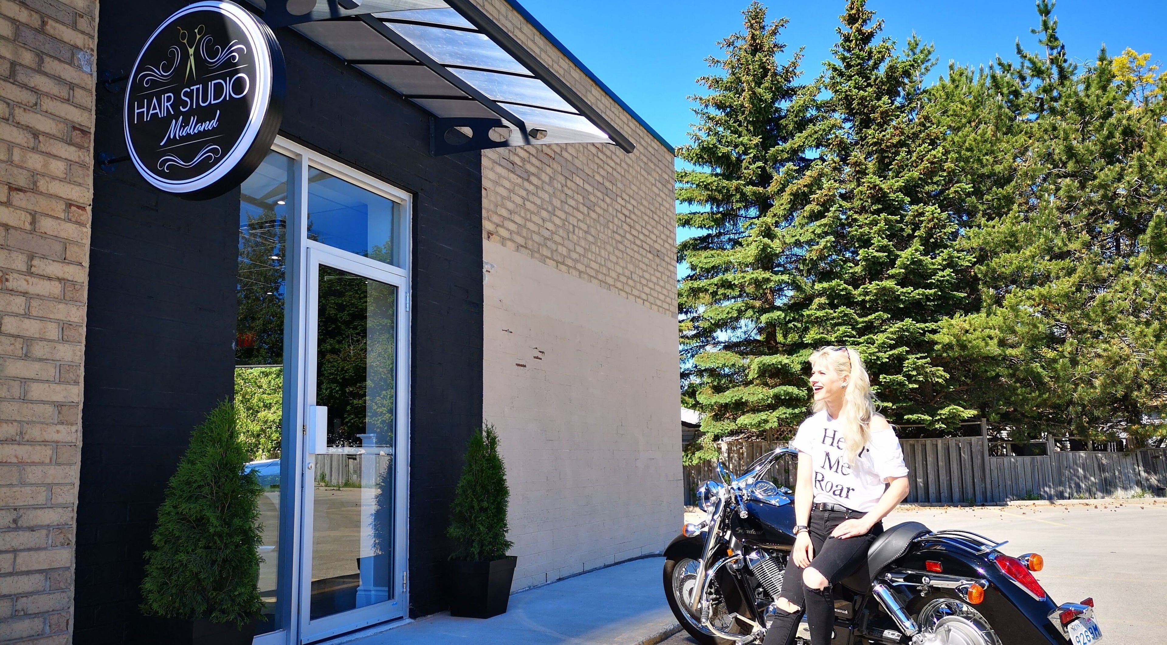 Front of Hair Studio Midland, Midland, Ontario, CA with a woman sitting on a motorcycle.